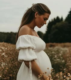 a pregnant woman is standing in a field