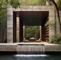 a small waterfall in the middle of a pool next to a building with bookshelves