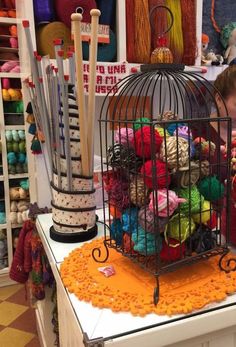 a woman is looking at yarn in a birdcage