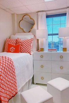 a bedroom with red and white bedding, dressers, mirror and window in it