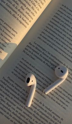 two white earbuds laying on top of an open book