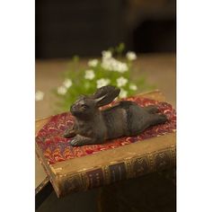 a rabbit figurine sitting on top of an old book with flowers in the background