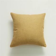 a yellow pillow sitting on top of a white wall