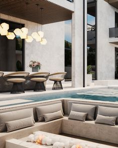 an outdoor seating area next to a swimming pool with fire pit in the middle and chairs around it