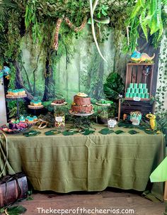 a jungle themed dessert table with lots of food and decorations on it's sides