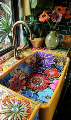 a colorful sink in front of a window with flowers on it