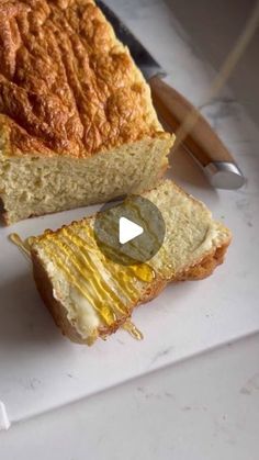 two pieces of bread on a cutting board with a knife next to it and another piece of bread in the background