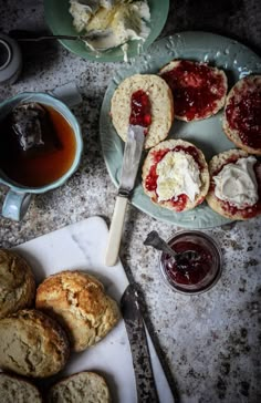 various pastries and jams on a table with spoon, knife and cup of tea