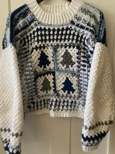 a white and blue sweater hanging on a door