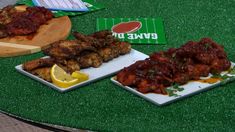 three plates of food sitting on top of a green table covered in grass next to a football field