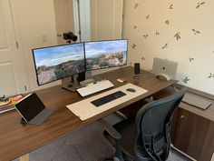 two computer monitors sitting on top of a wooden desk