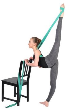 a woman is doing yoga on a chair with a green belt around her neck and legs