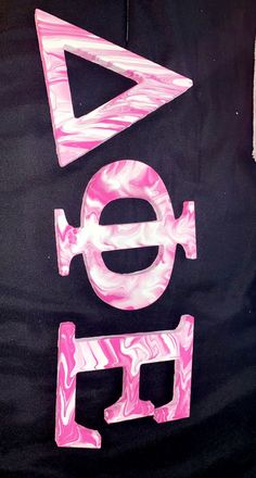 the letters are made out of pink and black marbled paper on a black background