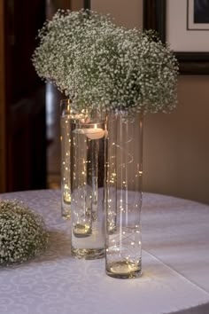 two tall vases with baby's breath flowers on a table