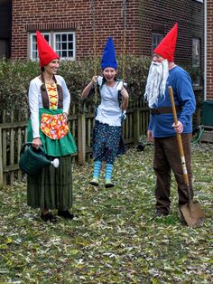 three people dressed as gnomes in front of a house