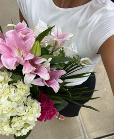 a woman holding a bouquet of flowers in her hands on the ground with other flowers