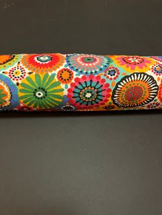 an orange, blue, and green flowered case on a black surface with a white background