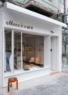 a storefront with chairs and tables in front of the shop's glass windows