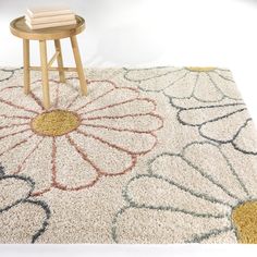 a table with two books on top of it next to a flower rug and stool