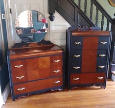 two dressers with mirrors on them in front of a stair case and handrail