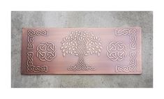 a metal plaque with an image of a tree in the center and celtic knots around it