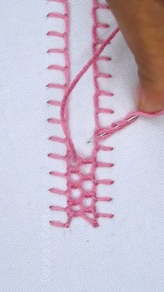 someone is working on a piece of pink thread