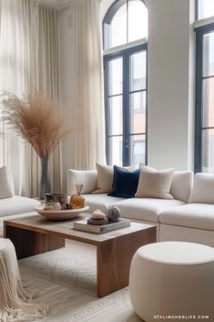 a living room filled with white furniture and large windows next to a window sill