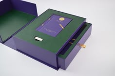 a purple and green box with a pen in it on a white table next to another box