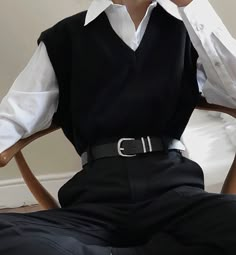 a woman sitting in a chair wearing a black dress shirt and white collared shirt