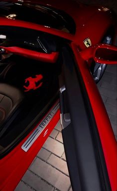 the interior of a red sports car with ferrari emblems on it's doors