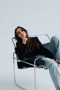 a woman sitting in a chair with her hand on her chin