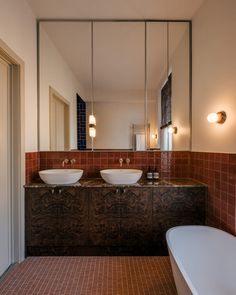 a bathroom with two sinks, mirrors and a bathtub next to each other in front of a large mirror