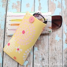 a pair of sunglasses sitting on top of a wooden table next to a yellow case