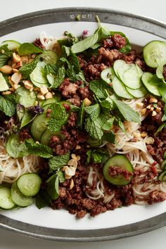 a plate filled with noodles, cucumbers and other veggies on top of it