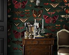 a room with a chair, table and wallpaper that has moths all over it