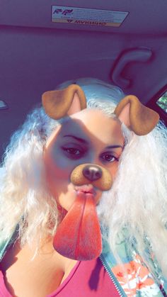 a woman with white hair and dog ears sticking her tongue out in the back seat of a car