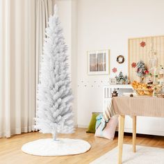 a white christmas tree in the middle of a living room next to a dining table