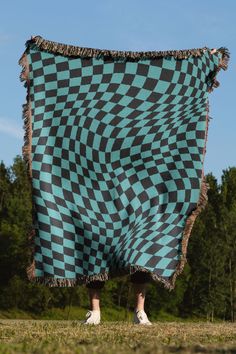 a person standing in the grass holding a blanket