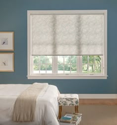 a bedroom with blue walls and white bedding, two windows covered in roman shades