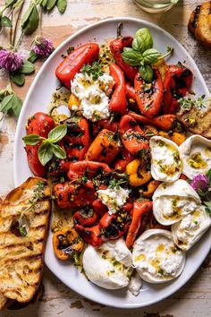 a white plate topped with tomatoes and mozzarella next to some toasted bread