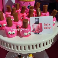 there is a pink cake with lots of eyes on it and a sign that says polyty polish