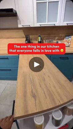 a person is writing on a piece of wood in the middle of a kitchen with blue cabinets