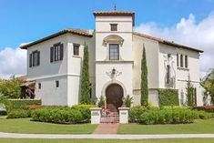 a large white house surrounded by lush green trees