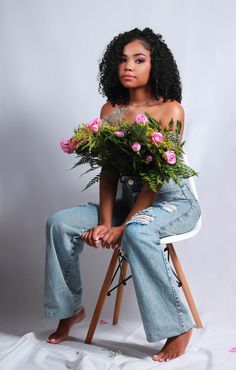 a woman sitting on a chair with flowers in her lap