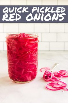 a jar filled with pickled red onions on top of a counter next to a spoon