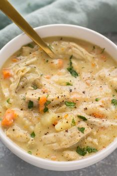 a bowl of chicken and dumpling soup with a gold spoon in it on a blue towel