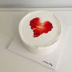 a white cake with red icing and a heart cut out on it's side