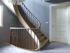 an empty room with a staircase and chandelier in the corner, next to a door