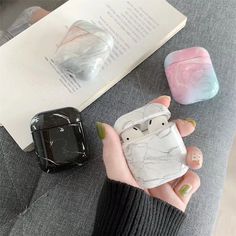 a woman is holding an airpods case in her hand