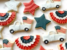 decorated cookies in the shape of american flags and trucks on a white tablecloth with red, white and blue decorations